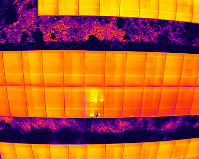 Termograma aéreo de fileiras de módulos fotovoltaicos com células em hotspot visíveis individualmente